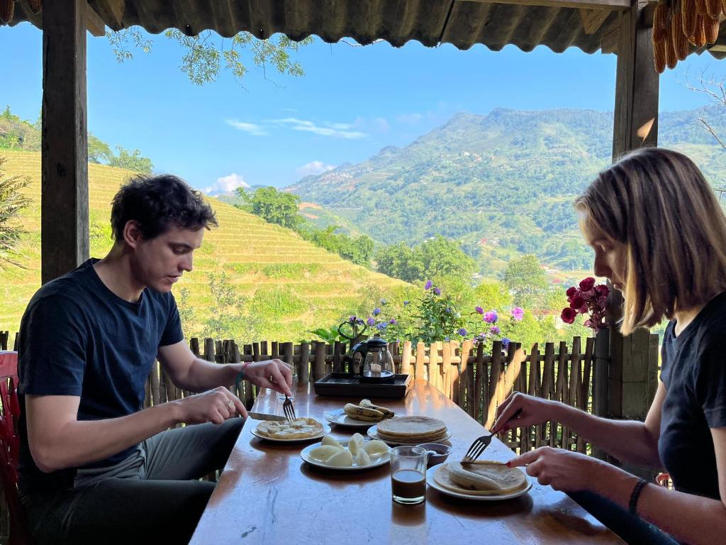 a group of people sitting at a table eating food at SaPa Big Tree Hmong Homestay in Sa Pa