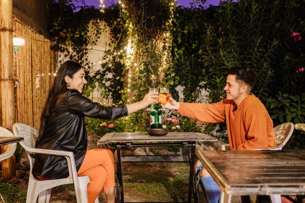un hombre y una mujer sentados en una mesa bebiendo vino en Hostal Namaste en Salta