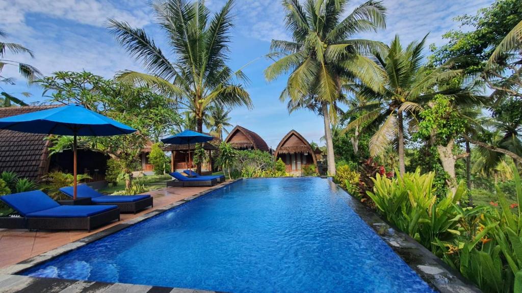a swimming pool in a resort with palm trees at Kelingking Tatakan Bungalow in Nusa Penida