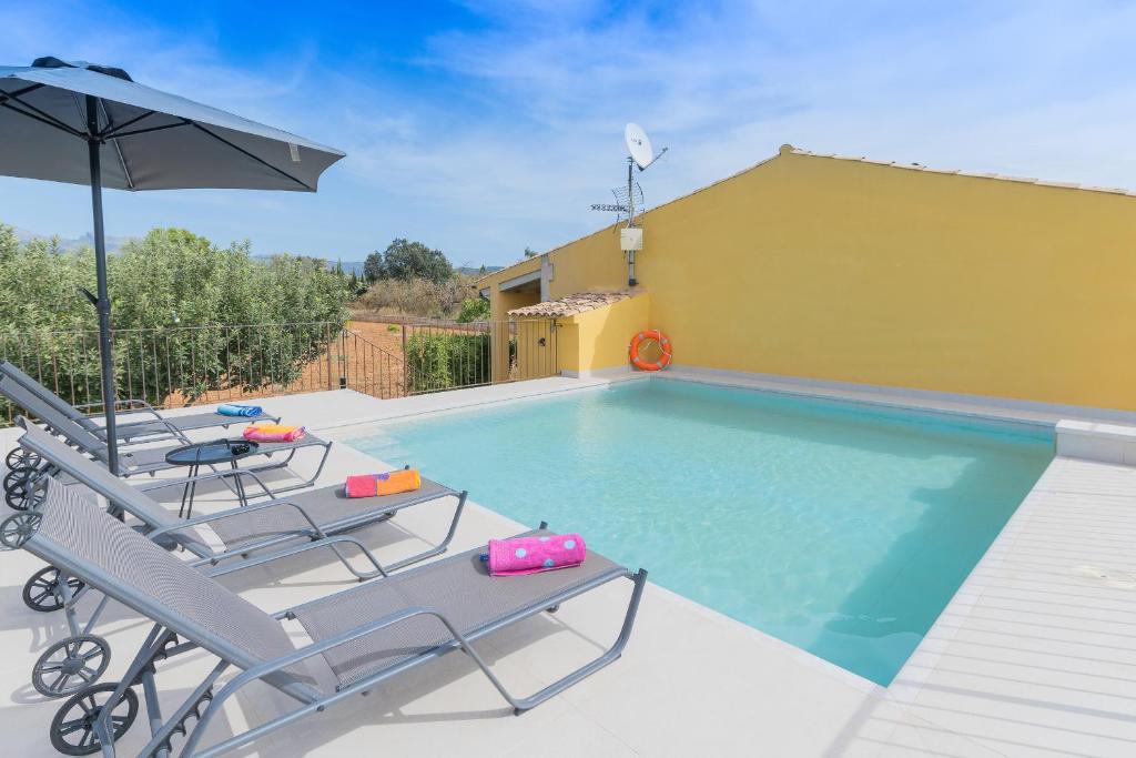 a swimming pool with two chairs and an umbrella at CANA MARTINA in Búger