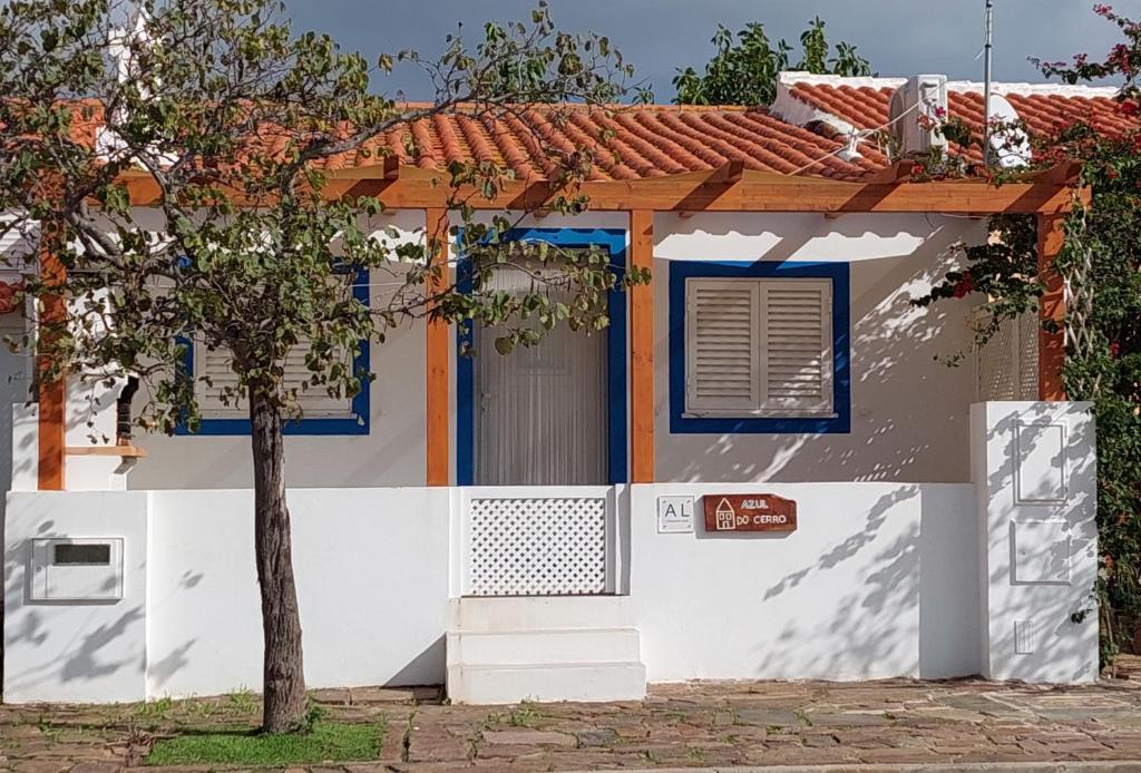 een wit huis met blauwe ramen en een boom bij Casa Azul do Cerro in Campeiros