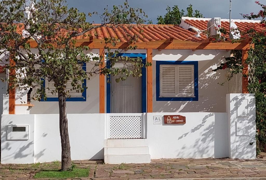 a white house with blue windows and a tree at Casa Azul do Cerro in Campeiros