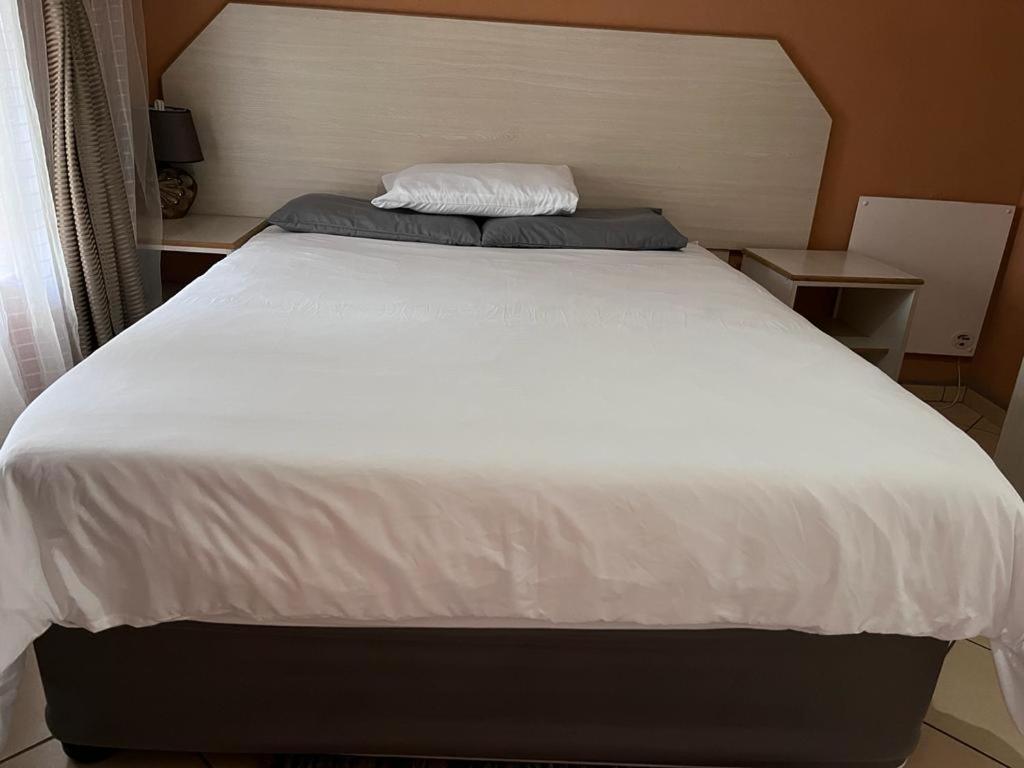 Cette chambre comprend un grand lit blanc et deux tables. dans l'établissement Izinjiki Namacusi Guest Farm, à Amsterdam