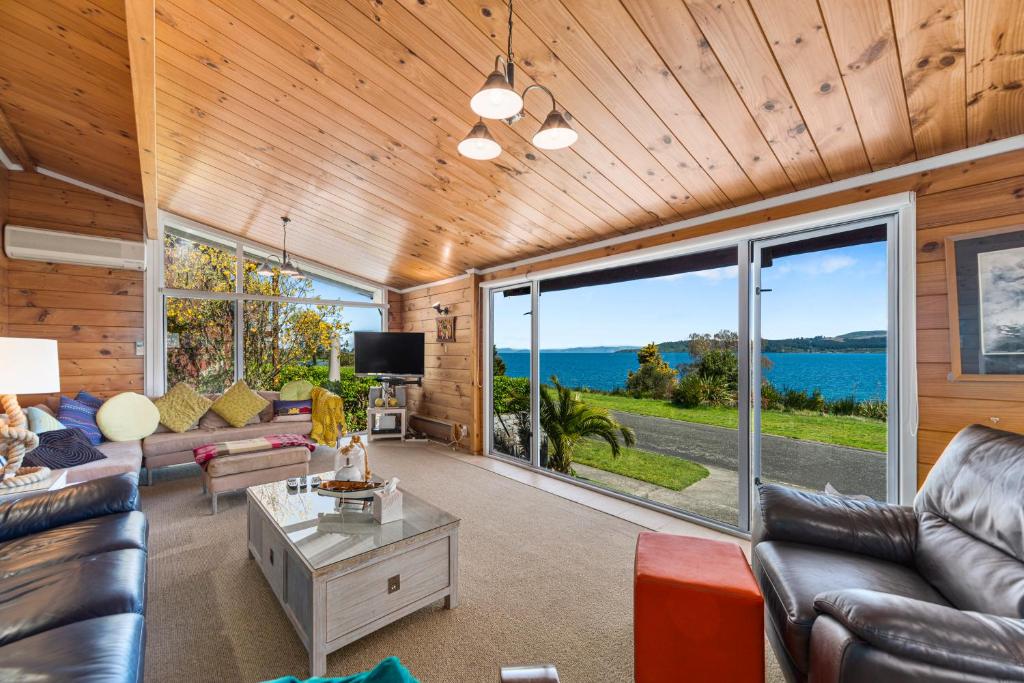 a living room with leather furniture and large windows at Barne the Bentley - Taupo Holiday Home in Taupo