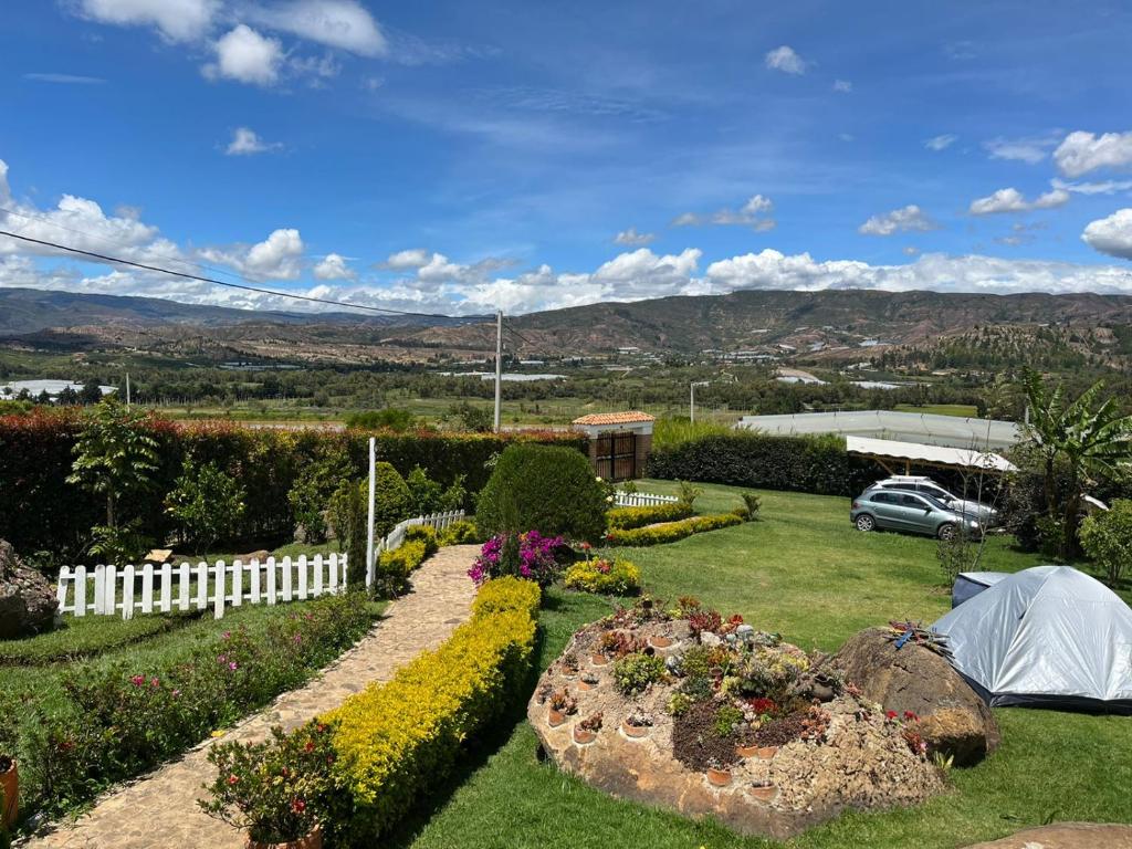 un jardin avec une clôture blanche et des fleurs dans l'établissement CABAÑA LOS JUANES, à Sutamarchán