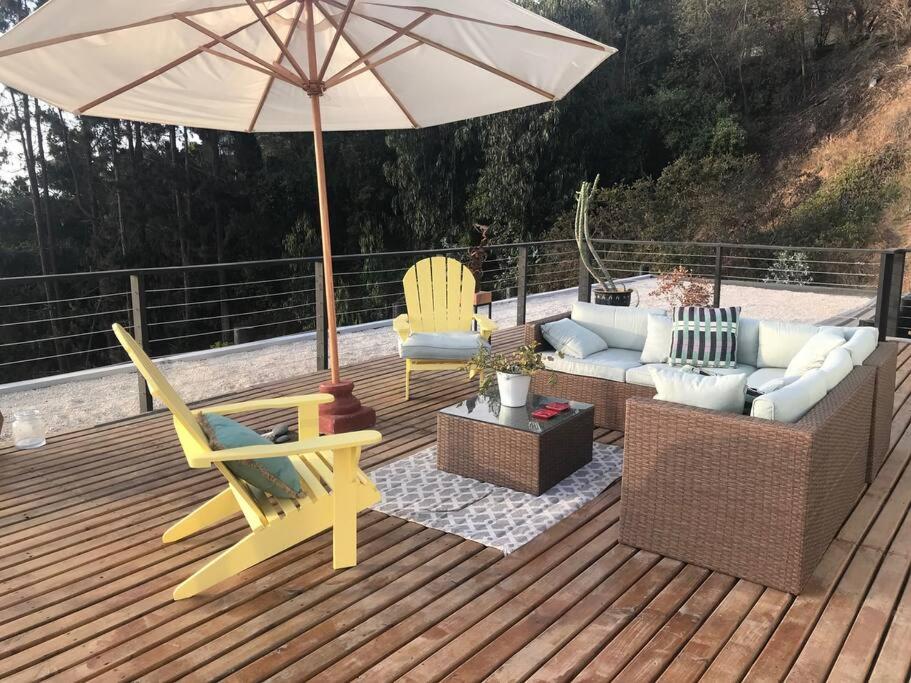 a deck with a couch and chairs and an umbrella at Espectacular Loft en Zapallar in Zapallar