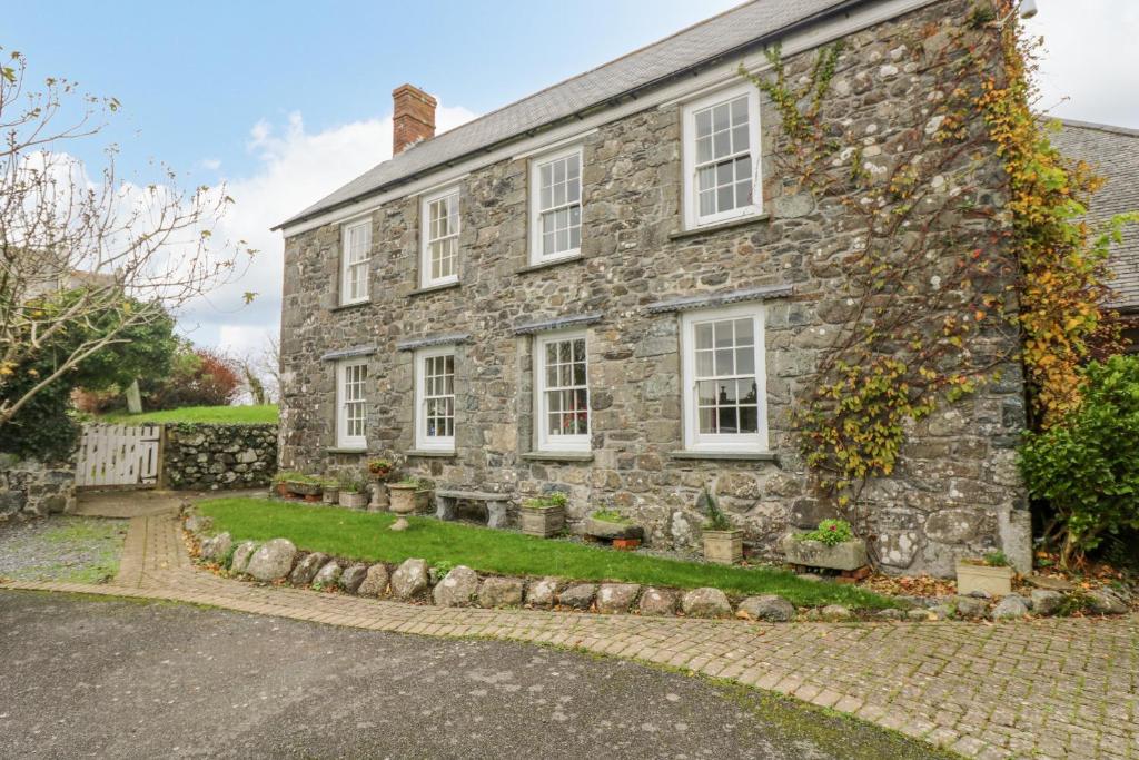 an old stone house with white windows on a street at Eden House Wing in Saint Keverne