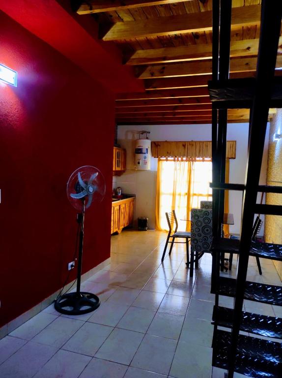 a living room with a red wall and a floor fan at Departamento 1 ambientes amueblado rafael calzada zona sur in Rafael Calzada