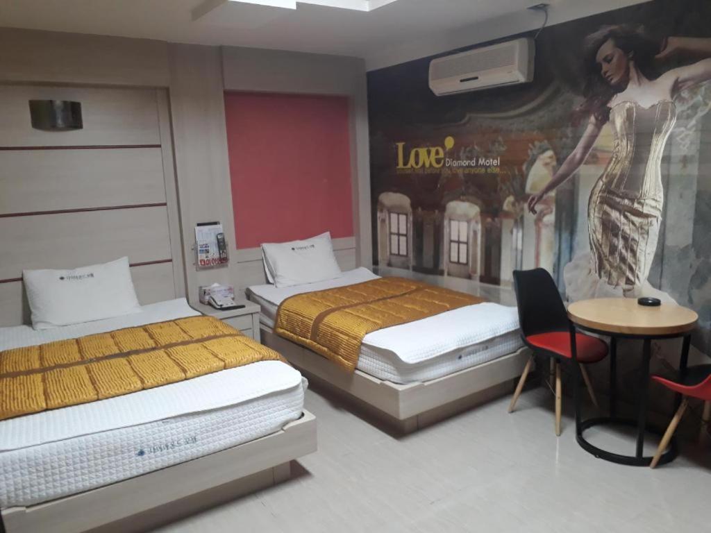 Habitación con 2 camas y una pintura en la pared. en Diamond Motel, en Sacheon