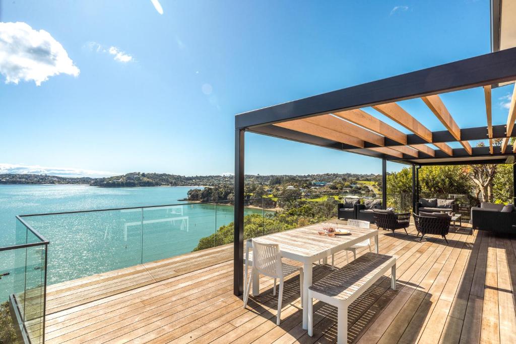 an outdoor deck with a table and chairs and the water at Moana Retreat in Putaki Bay