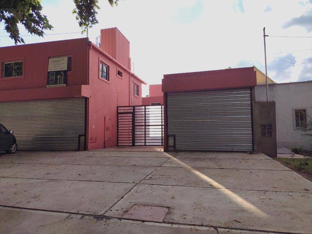 two garage doors in a parking lot next to a pink building at Aladdín Departamentos in Ciudad Lujan de Cuyo