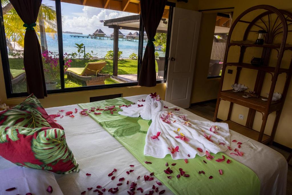 a bed with flowers on it with a view of the ocean at Fare Manava in Bora Bora