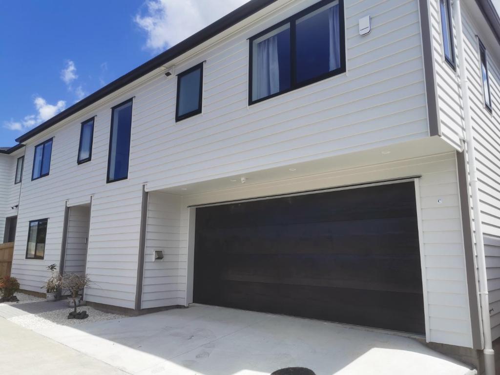 uma casa branca com garagem em Lovely House in Central Papatoetoe em Auckland