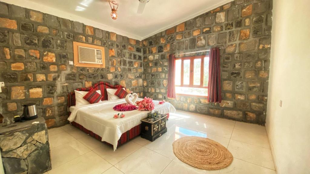 1 dormitorio con 1 cama en una habitación con paredes de piedra en Jabal Shams Mountain Rest House, en Al Hūb