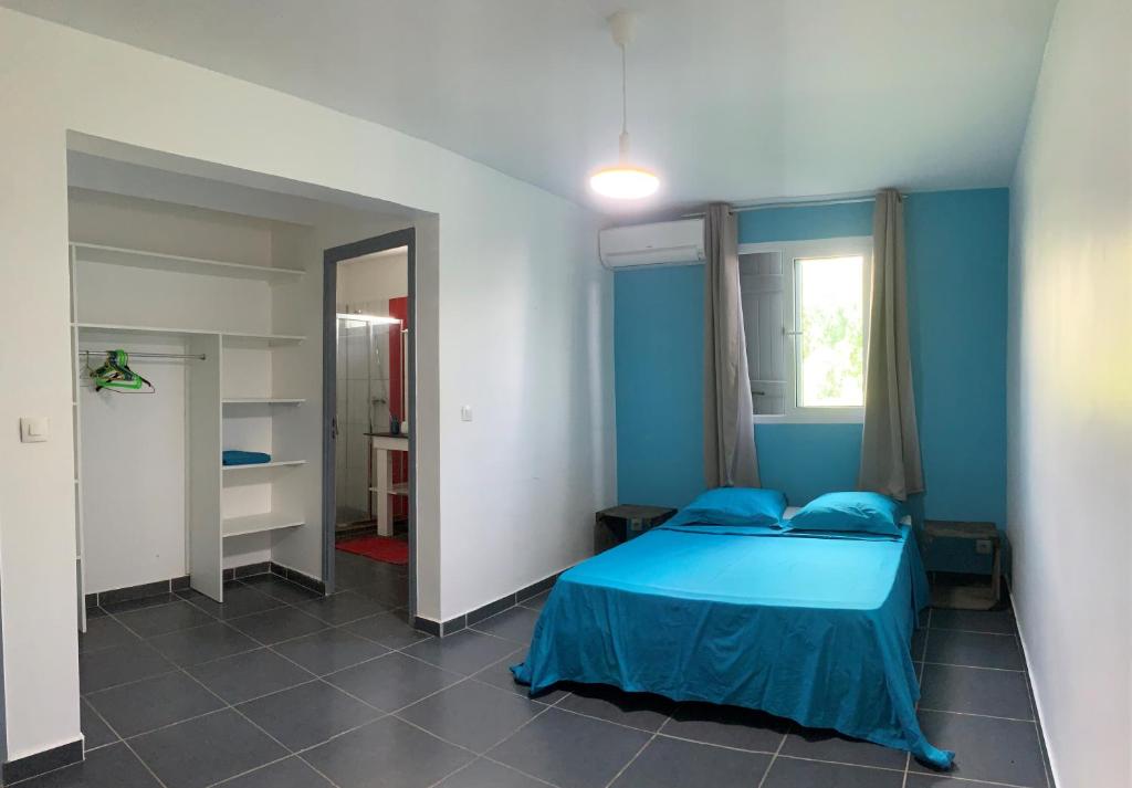a blue bedroom with a bed and a window at Villa Lanar'am in Bouillante