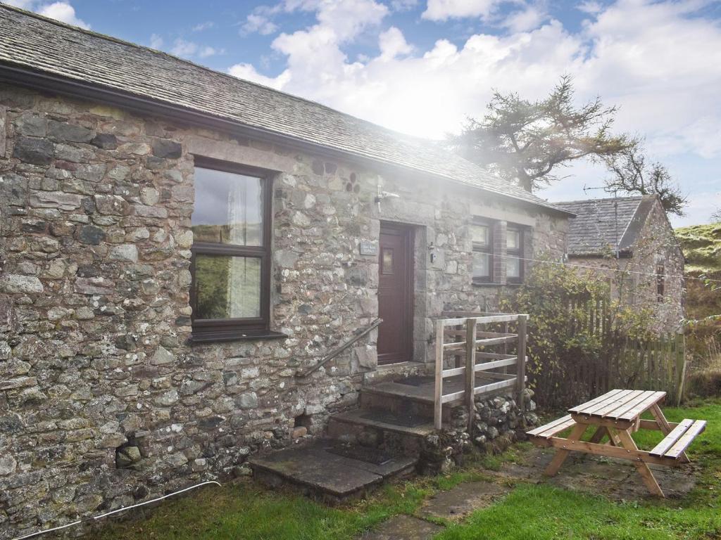 a stone house with a wooden bench next to it at Uk39800 - Crag Barn in Troutbeck