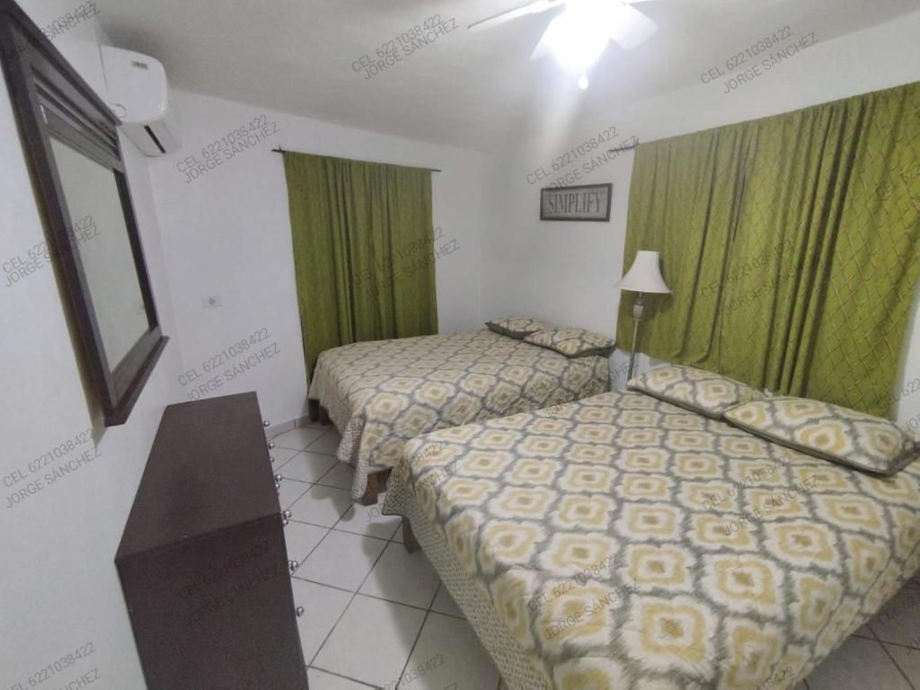 2 camas en una habitación de hotel con cortinas verdes en Casa Tecalai 5 en San Carlos