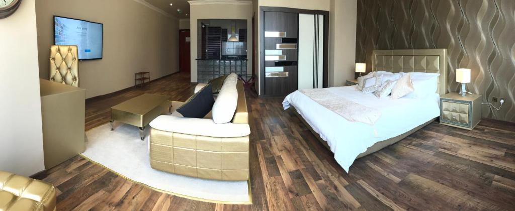 a bedroom with a bed and a chair and a couch at Wakra Inn Hotel Apartments in Al Wakrah