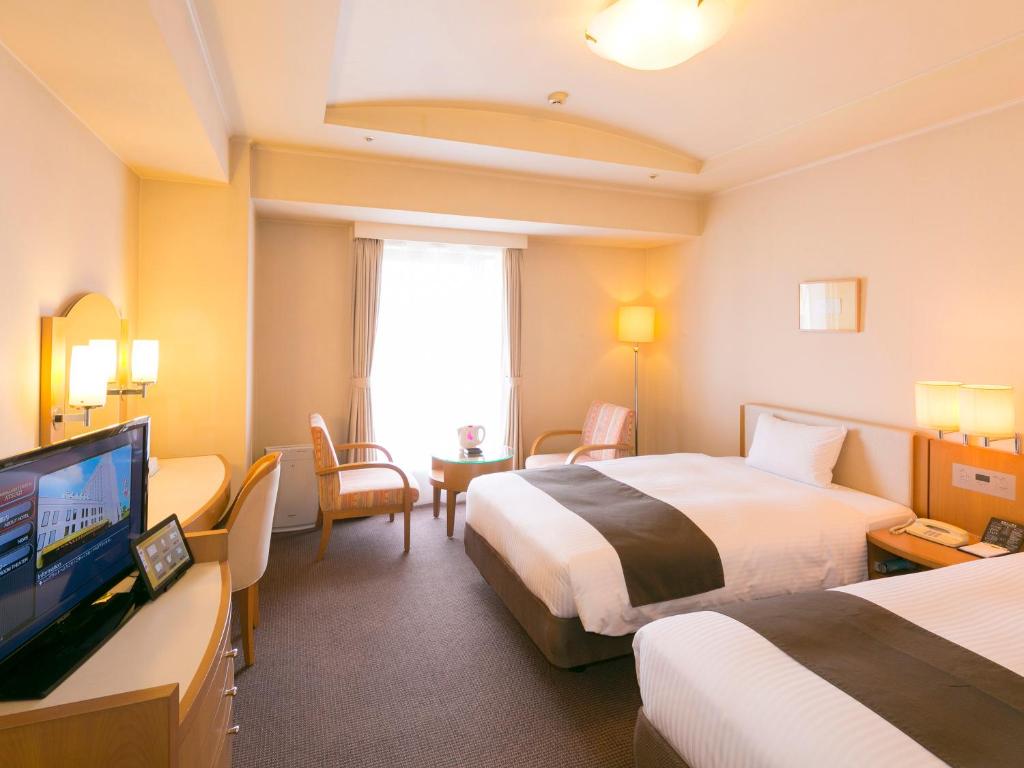 a hotel room with two beds and a flat screen tv at Rembrandt Hotel Atsugi in Atsugi
