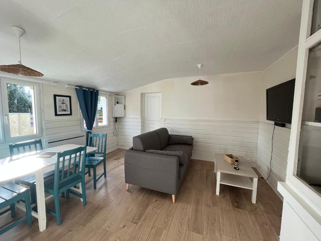 ein Wohnzimmer mit einem Sofa und einem Tisch in der Unterkunft La ptite maison de Royan pour 4 personnes avec jardin in Royan