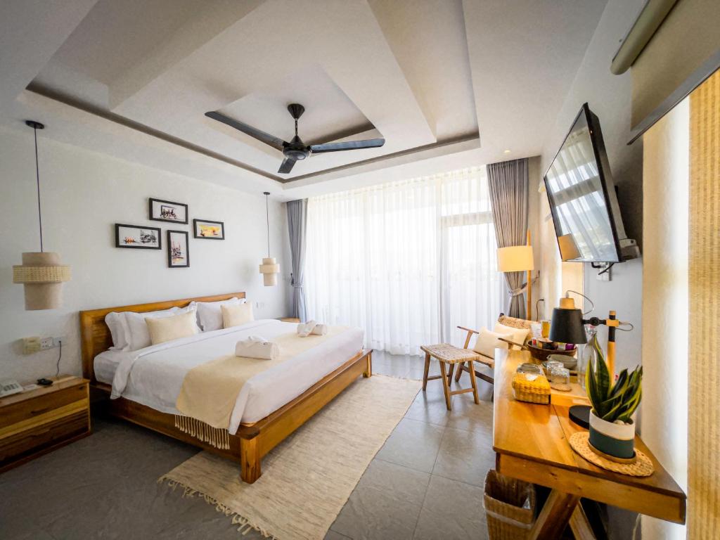 a bedroom with a bed and a desk and a television at Montagne Boutique in Kampot