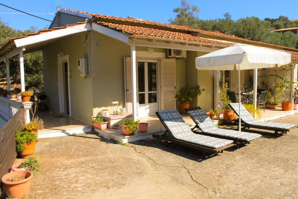 a house with two lounge chairs and an umbrella at Amalia Apartment in Perítheia