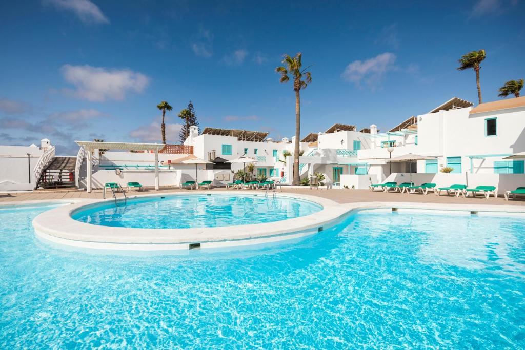 a large pool with blue water in front of white buildings at Smy Tahona Fuerteventura in Caleta De Fuste