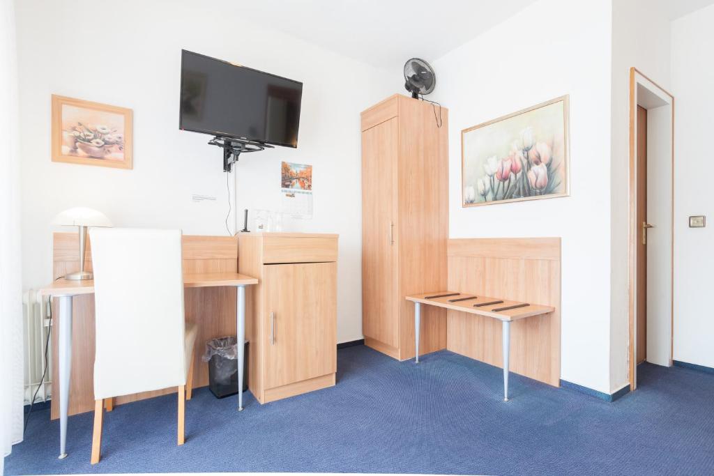 a room with a tv and a desk with a table at TM Hotel Dortmund Airport in Holzwickede