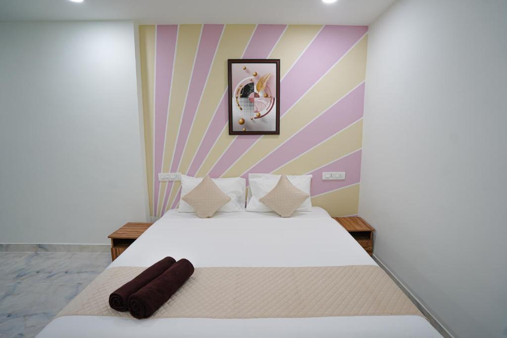 a bedroom with a white bed with a striped wall at MAHASRI Studio Apartments- Brand New Fully Furnished Air Conditioned Studio Apartments in Tirupati