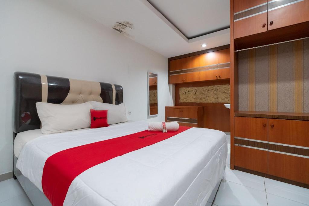 una camera da letto con un grande letto bianco con una coperta rossa di RedDoorz near RSIA Andini Pekanbaru a Pekanbaru