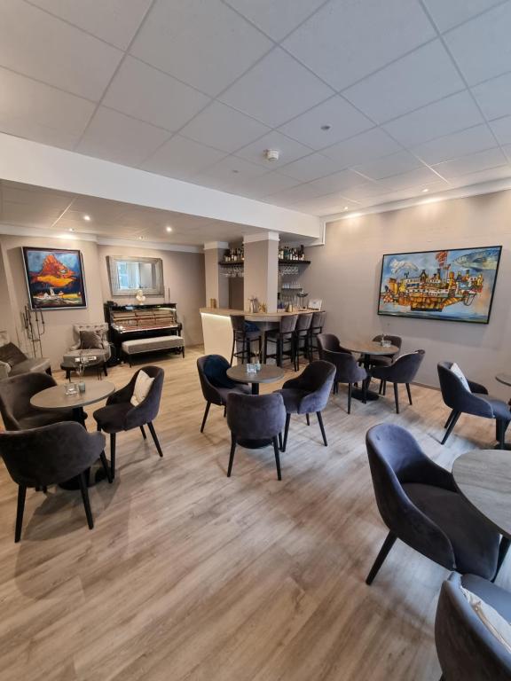 a waiting room with tables and chairs and a piano at Hotel Diamant in Wedel