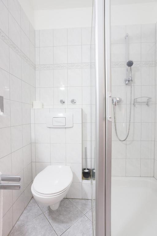 a white bathroom with a toilet and a shower at TM Hotel Dortmund Airport in Holzwickede