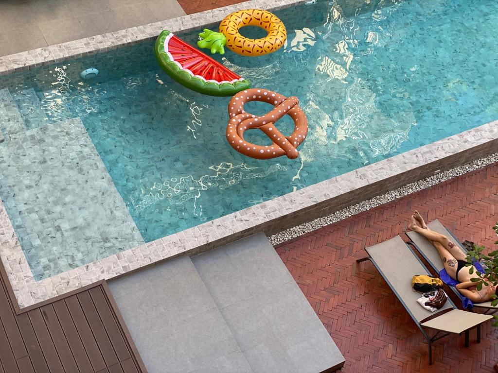an overhead view of a swimming pool with two people in a chair and an orange at Issara by D Hostel in Bangkok