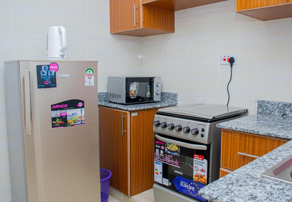 a kitchen with a refrigerator and a stove at Pearl Suites Apartments in Nakuru