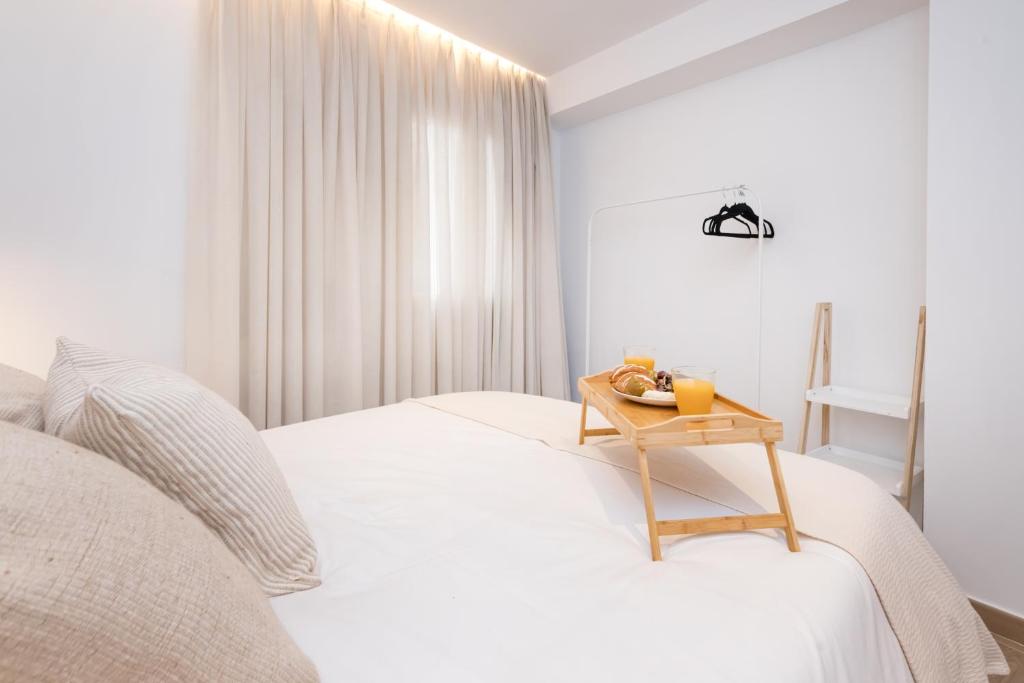 biała sypialnia z łóżkiem z drewnianym stołem w obiekcie Amargura City Center Apartment w Maladze