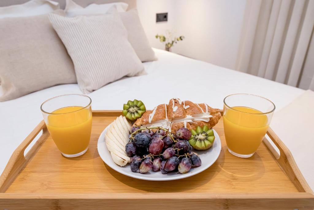 talerz jedzenia na tacy z dwoma kieliszkami soku pomarańczowego w obiekcie Amargura City Center Apartment w Maladze