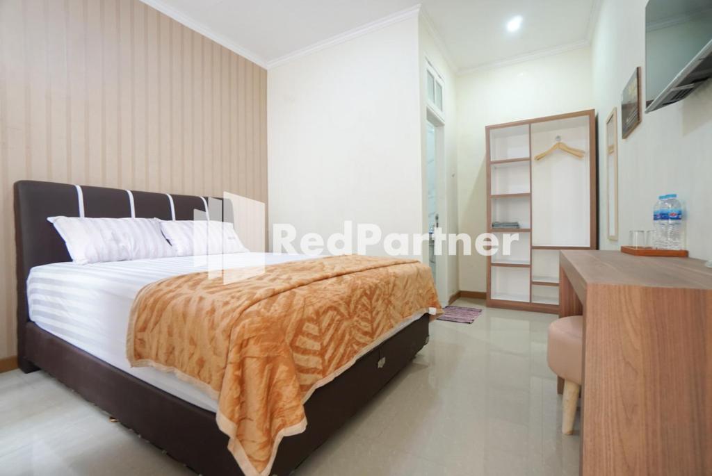 a bedroom with a bed and a desk and a mirror at Fazza Syariah Mitra RedDoorz in Jakarta