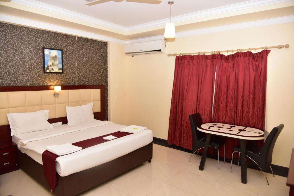 um quarto de hotel com uma cama e uma mesa em Ananya Comfortss em Hospet