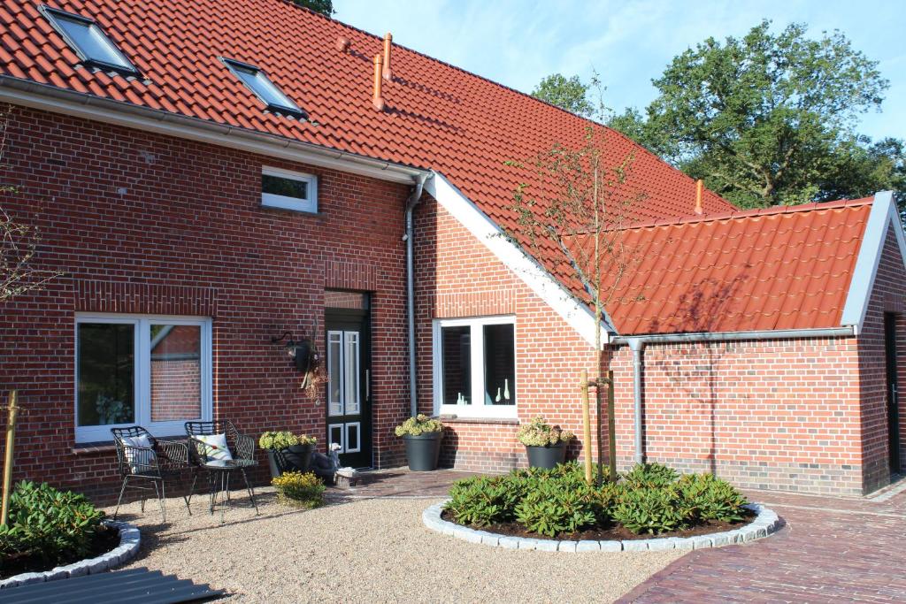 a brick house with a red roof and some plants at Ferienwohnung "Moi Tied" 35222 in Hesel