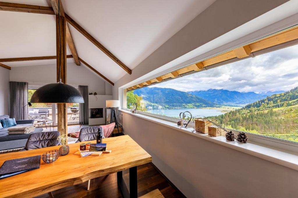 a living room with a table and a large window at der Sonnberg - Alpinlodges in Zell am See