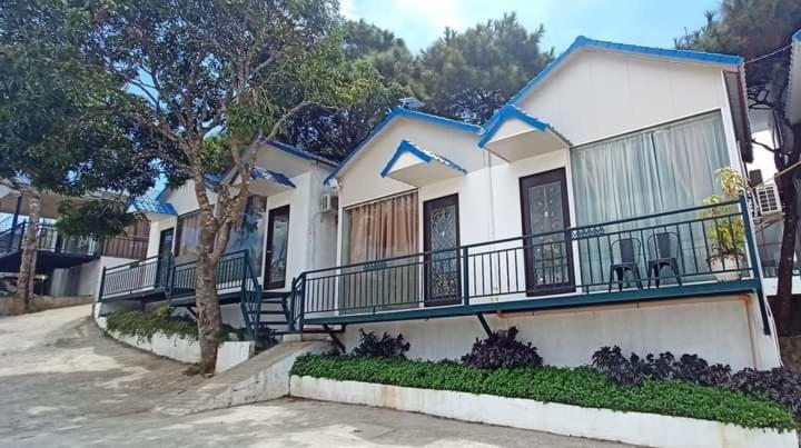 een wit huis met een balkon en een boom bij Brilliant Sky in Tagaytay