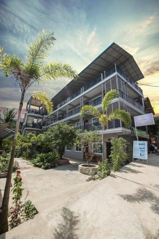 ロン島にあるRoomy Guesthouseのヤシの木が目の前に広がる建物