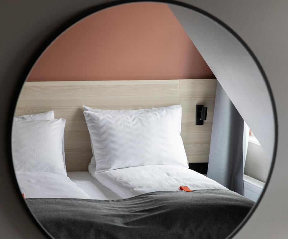 a mirror reflecting a bed with white sheets and pillows at Citybox Oslo in Oslo