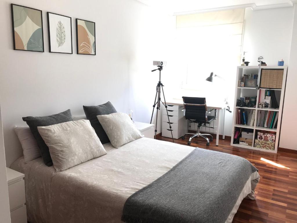 um quarto com uma cama e uma secretária com uma máquina fotográfica em Habitación Relax em Milladoiro