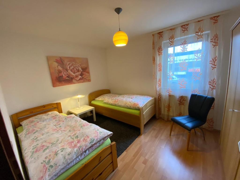 een slaapkamer met 2 bedden, een stoel en een raam bij City Apartment in Nürnberg Am Plärrer in Neurenberg