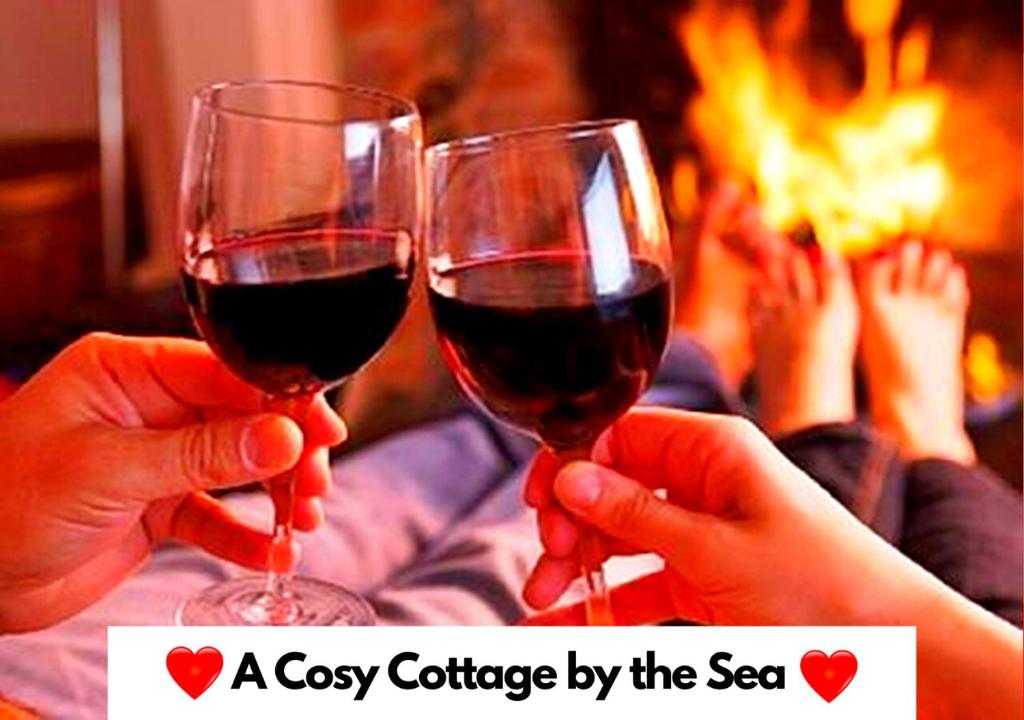 two people holding glasses of red wine in front of a fire at Fisherman's Cottage - The Ultimate Romantic Lakeside Cottage just a few steps from the Beach! Relax with a glass of wine & Snuggle up to the Cosy Log Burner at the BEST Location in Mablethorpe! It's Pet Friendly too! in Mablethorpe