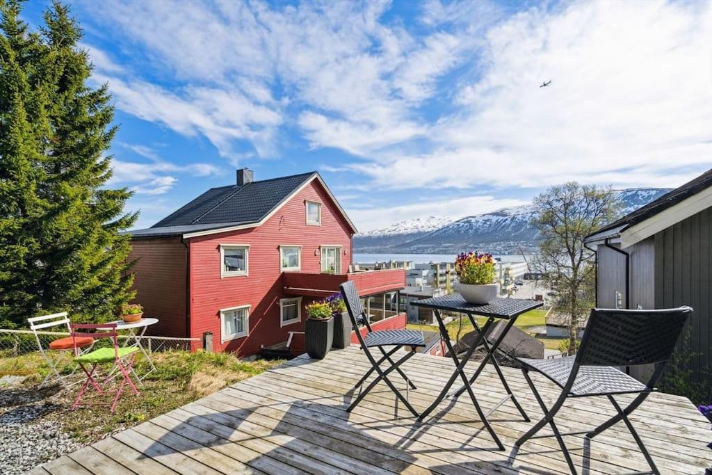 a patio with a table and chairs and a red house at Cozy little house in Tromsø city in Tromsø