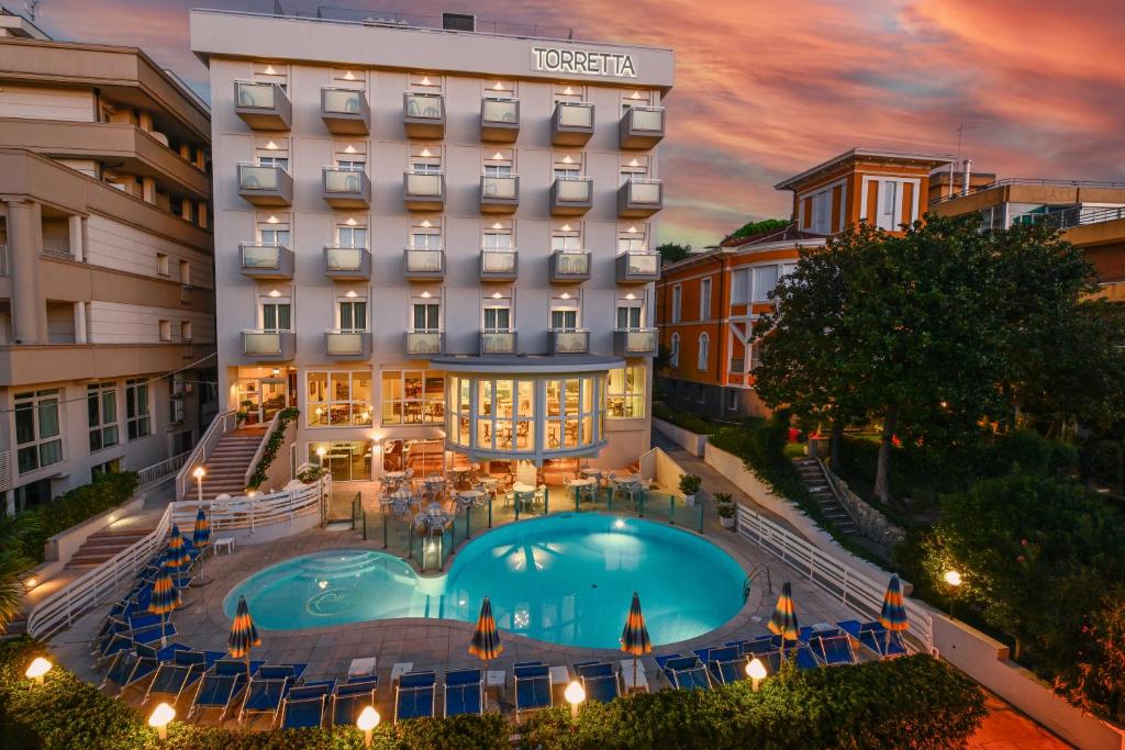 un hôtel avec une piscine en face d'un bâtiment dans l'établissement Hotel Torretta, à Cattolica