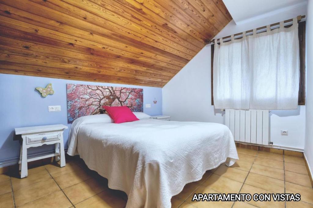 una camera con letto bianco e soffitto in legno di Apartamentos Taüll a Tahull