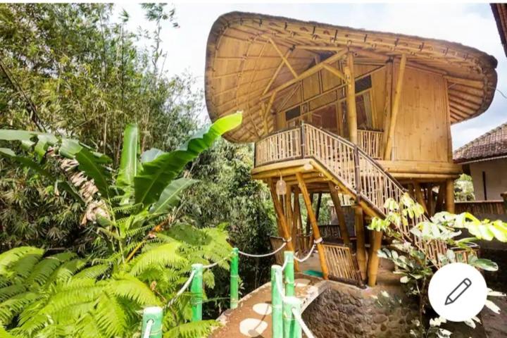 a large tree house with a large deck in a garden at Pondok Salacca#bamboohouse# in Candidasa